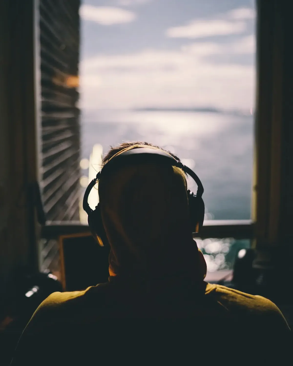 A man wears noise cancelling headphones while looking out of a window