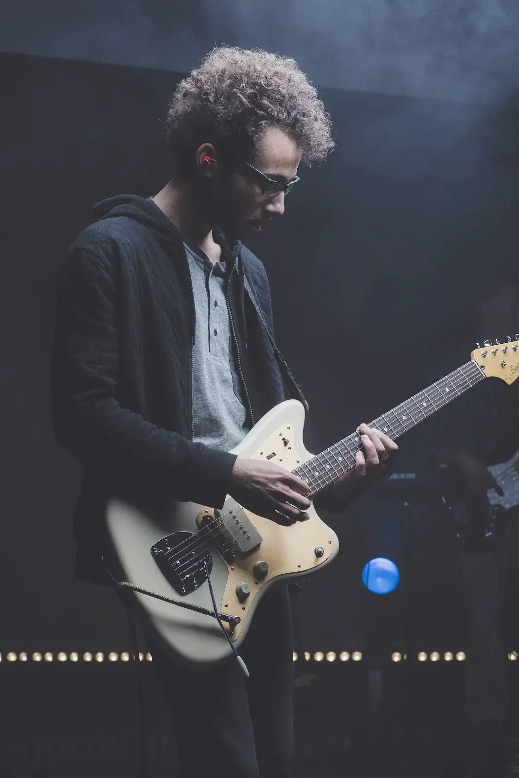 A guitarist wears in ear monitors while performing